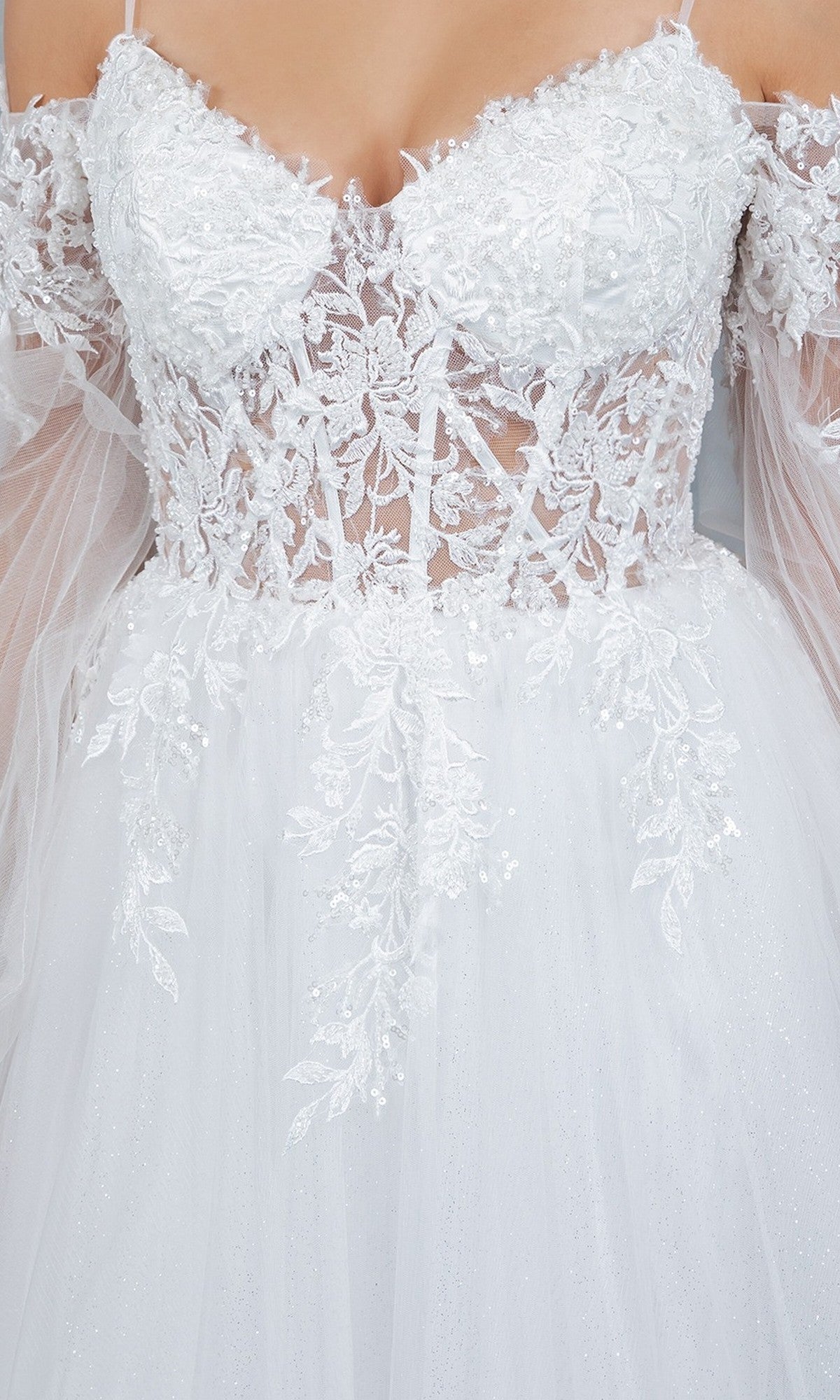 Close-up of the Long Formal Dress: Cinderella Couture 4234, a white gown showcasing a sheer lace bodice with delicate appliqué, floral embroidery, and off-the-shoulder tulle sleeves.